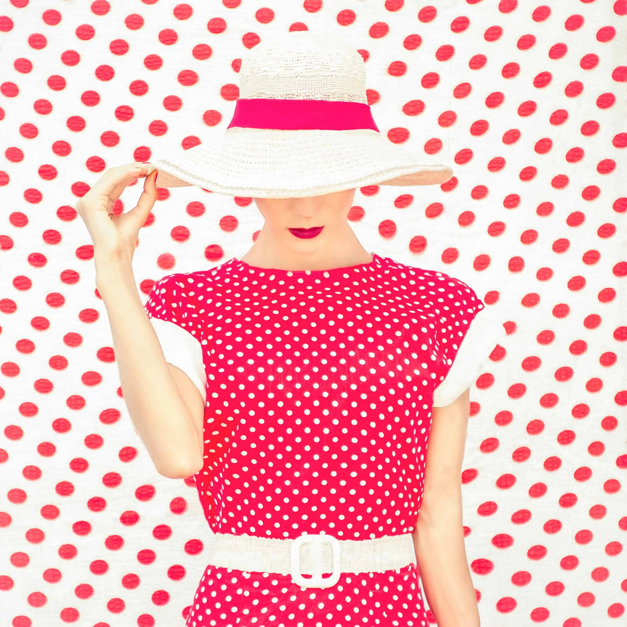 A model wearing an inverted polka dot dress with a polka dot backdrop.