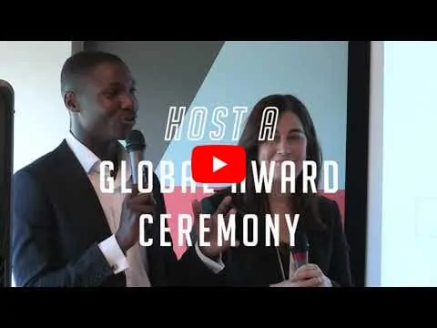Two speakers at an award events, one male, one female. Both holding wireless microphones.