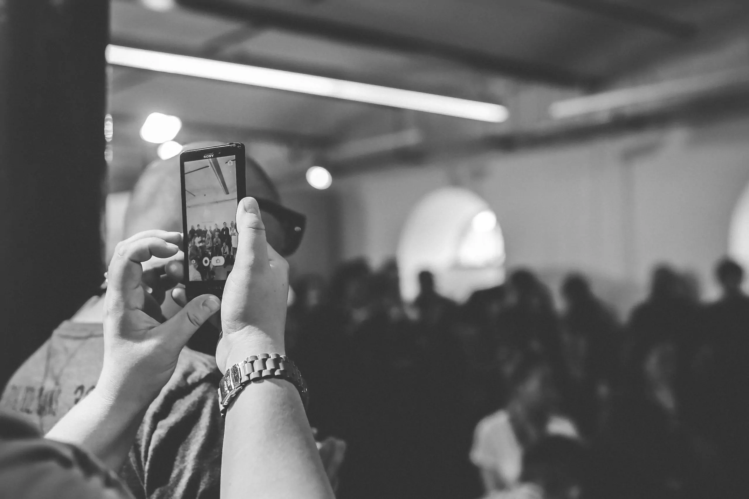 Woman taking a photo with cell phone / bw