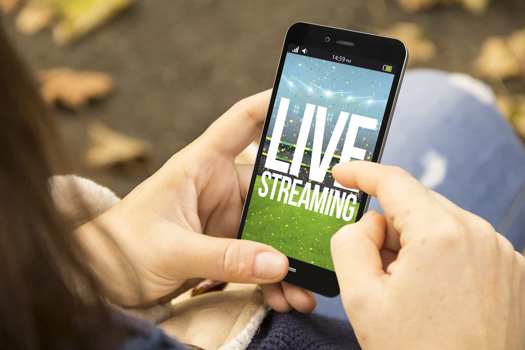 Live Streaming Services A person holding their mobile phone upright whilst interacting with the touch screen