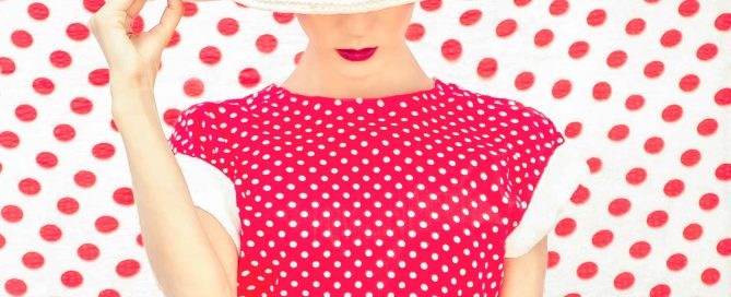 A model wearing an inverted polka dot dress with a polka dot backdrop.