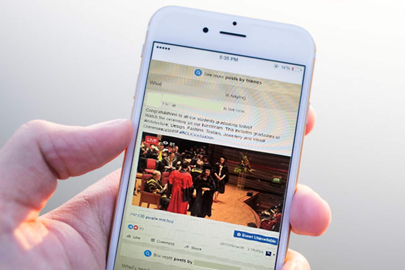 Facebook Live – Facebook Video Streams A mobile phone in a users hand. The phone screen shows a popular social media site.