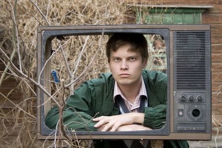 Live Business Stream – 5 Reasons for Priority Focus A slightly grumpy looking man looking through the shell of a broken television without a screen.